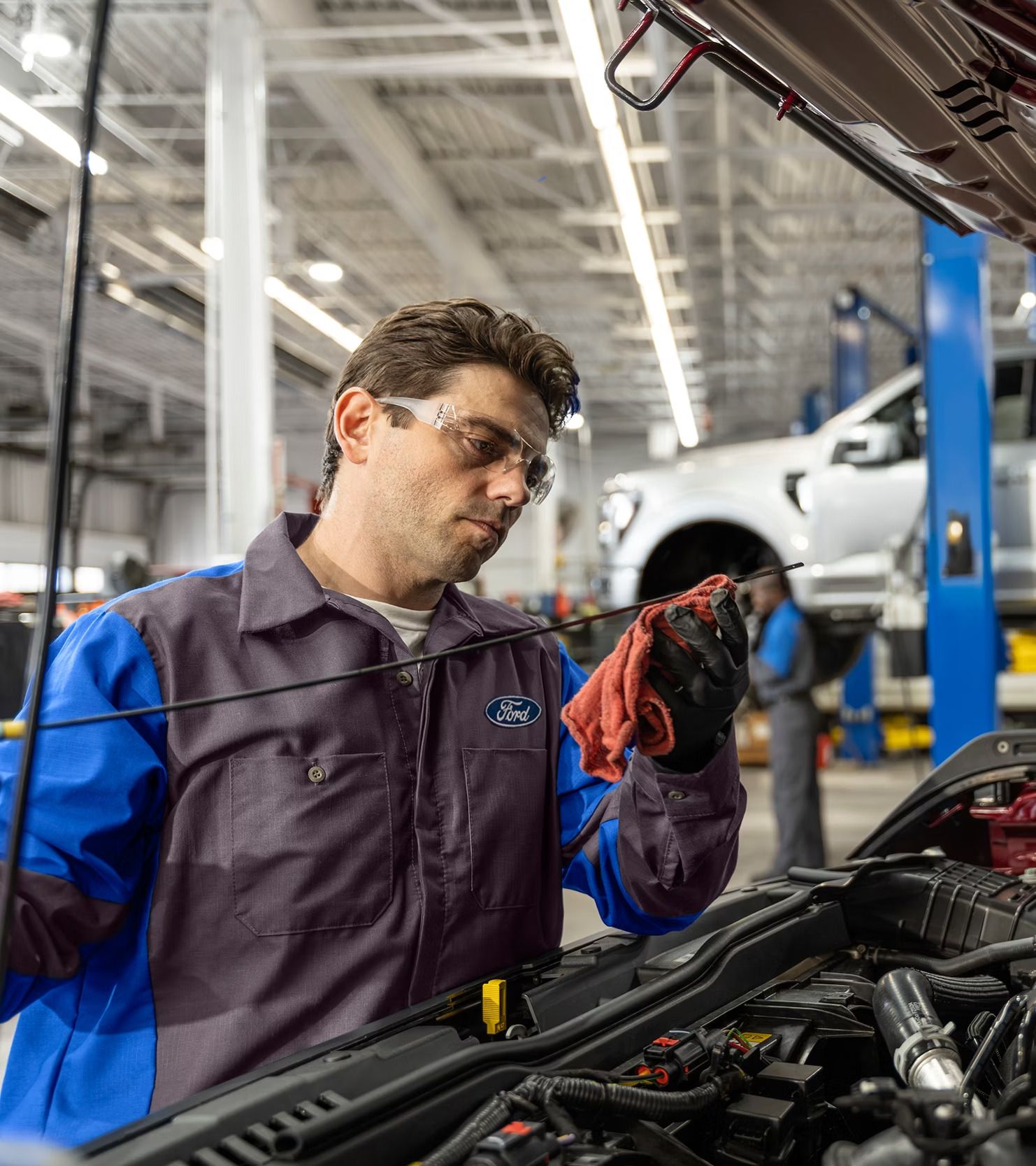Ford technician checking the engine oil dipstick under an open hood